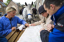 Horses and riders checking the map outside the Three Horseshoes Pub on a horseriding holiday, Brecon Beacons National Park, Po-wys, Wales, UK, Model released