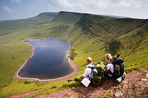 Walkers relaxing atbove Llyn y Fan Fach, a glacial cirque, beneath Black Mountain in the Brecon Beacons National Park, Powys, Wales