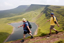 Walkers hiking above Llyn y Fan Fach,  a glacial cirque, beneath Black Mountain in the Brecon Beacons National Park, Powys, Wales