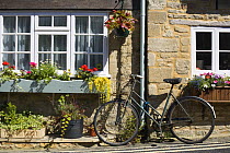 Old fashioned bicycle outside a cottage in summer, Burford, Cotswolds, Oxfordshire, UK