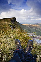 Walkers boots and view of Fan Hir escarpment, Brecon Beacons National Park, Powys, Wales