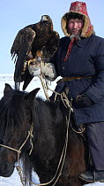 Kazakh hunter on horseback with Golden eagle (Aquila chrysaetos), Xinjiang Province, North-west China. February 2007, BBC "Wild China" series