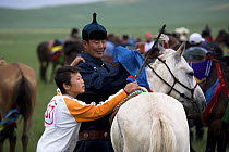Mongolian boy and his father preparing for a horse race at the annual Nadam Festival. Inner Mongolia, Northern China. June 2006, BBC "Wild China" series