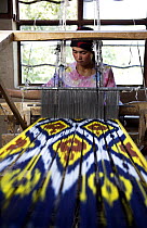 Woman silk weaving on a wooden loom at Hotan (Hetian), a town along the ancient Silk Road. Xinjiang Province, North-west China. July 2006, BBC "Wild China" series