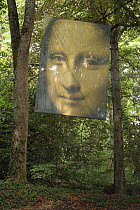 Part of Mona Lisa painting enlarged and hanging between trees. Leonardo da Vinci Museum at the Castle of Clos Lucé, Amboise, France