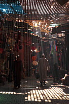 Man walking beneath shafts of sunlight in Souk of Marrakech market, Morocco December 2007