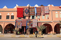 Man cycling past a rug shop in Agdz, Drâa Valley, Morocco December 2007