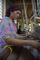 Woman silk weaving with natural dyes on a wooden loom at Hotan (Hetian), a town along the ancient Silk Road. Xinjiang Province, North-west China. July 2006