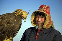 Portrait of Kazakh hunter with his Golden eagle, the Altai mountains of Xinjiang Province, north-west China. February 2007