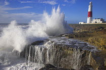 Waves crashing over the rocks at Portland Bill with lighthouse in the background, Dorset, UK