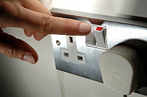 Person switching off electric switch at wall socket.