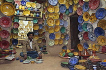 Ceramics shop with plates and bowls hanging from the walls. Tamegroutte, Drâa Valley, Morocco December 2007