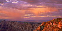 The setting sun highlights the viewpoint at Desert's View Watchtower, as rain showers pass by in the background. Grand Canyon National Park, Arizona