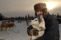 Musher hugging a sled dog / husky (Canis familiaris) in Manitoba, Canada