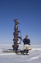 Inupiat guide Jack Kayotuk standing in front of a test well for crude oil, outside Prudhoe Bay along the Arctic coast, Alaska, 2007