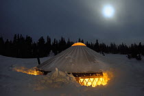 Yurt buried in snow at night under a full moon, Shoshone National Forest, Wyoming, USA