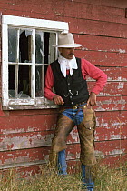 Cowboy leaning against wooden barn, Colorado, USA . Model released