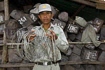 Ranger with confiscated snares in front of confiscated timber,  Preah Monivong Bokor National Park, Elephant Mountains, south-western Cambodia (formerly Kampuchea)