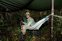 Guard on anti-poaching patrol sitting on hammock set up for overnight camp, Preah Monivong Bokor National Park, Elephant Mountains, south-western Cambodia (formerly Kampuchea)