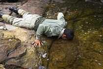 Guard on anti-poaching patrol drinking water from stream, Preah Monivong Bokor National Park, Elephant Mountains, south-western Cambodia (formerly Kampuchea)