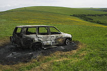 Burnt out abandoned vehicle on downland, South Downs (Area of Outstanding Natural Beauty), Sussex, UK