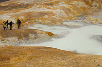 People photographing bubbling hot mud springs, geothermal area of Krafla, North Iceland