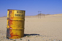 An old barrel at the diamond area border being used as a sign post warning people not to enter, Namib desert, Namibia