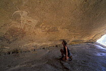 Woman looking at a Bushman painting of a white elephant in Philipp's Cave, Erongo Mountains, Damaraland, Namibia