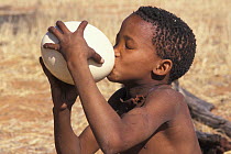 Young Bushman San drinking water from Ostrich egg, which is used to hold water, Bushmanland, Namibia