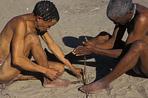 Two San Bushmen making fire with two pieces of wood, Bushmanland, Namibia