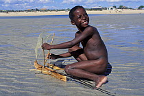 Vezo child playing on the beach with model pirogue, West Madagascar