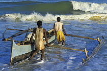 Vezo fishermen pushing pirogue / outrigger canoe into the sea, West Madagascar