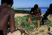 Vezo fishermen reparing fishing net on the beach, West Madagascar