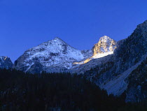 Sunlight illuminates a snow-covered rocky peak in d'Aiguestortes National Park, Pallars Sobira, Catalonia, Spanish Pyrenees