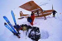 Skier Phil Atkinson unloads mountaineering gear from a ski plane on the Ruth Glacier, Denali National Park, Alaska, USA