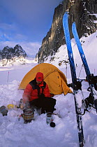 Skier Carl Gable cooks on a camp stove in front of his tent on the Ruth Glacier, Denali National Park, Alaska, USA