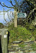 Public Footpath sign on wall with way marker signs on fence, North Cornwall, UK