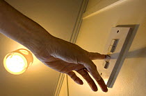 Person switching on / off an electric switch, UK