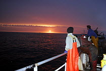 Fishermen watch the sun go down from a fishing vessel in the North Sea