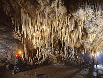 Potholer sitting in cave admiring stalactites, Avenc dels Topografs, Garraf-Ordal NP, Barcelona, Spain