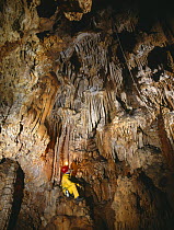 Potholer sitting in cave admiring stalactites, Avenc del Passant, Garraf-Ordal NP, Barcelona, Spain