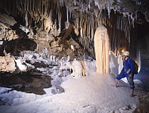 Potholer walking on mounds of salt crystals in cave, Cave Lachambre, Ria, Conflent, Pyrenees, France
