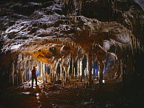 Potholer in cave admiring stalagmites and stalactites, Cueva Coventosa, Ason, Cantabria, Spain