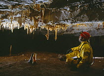 Potholer in cave admiring early formation of stalactites, Cantabria, Spain