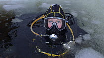 Ice diver surfacing from under the ice in the White sea, Northern Russia  March 2008