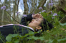 Woman relaxing amongst flowers at a Natural Environment for Business Event at the Avon Wildlife Trust Folly Farm Centre, Somerset, UK. Model released