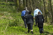 People in suits walking at edge of wood at a Natural Environment for Business Event at the Avon Wildlife Trust Folly Farm Centre, Somerset, UK. Model released