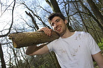 Volunteer carrying tree trunk on wildlife training course at the Avon Wildlife Trust Folly Farm Centre, Somerset, UK. Model released
