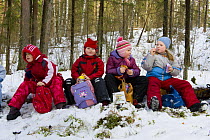 A group of Estonian school children in the woods learning about nature, sitting down eating and drinking, Tartumaa, Estonia