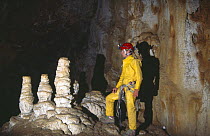 Potholer in underground cave system beside stalagmites, Graller del Boixaguer, Serra del Montsec, Lleida, Spain, October 1994